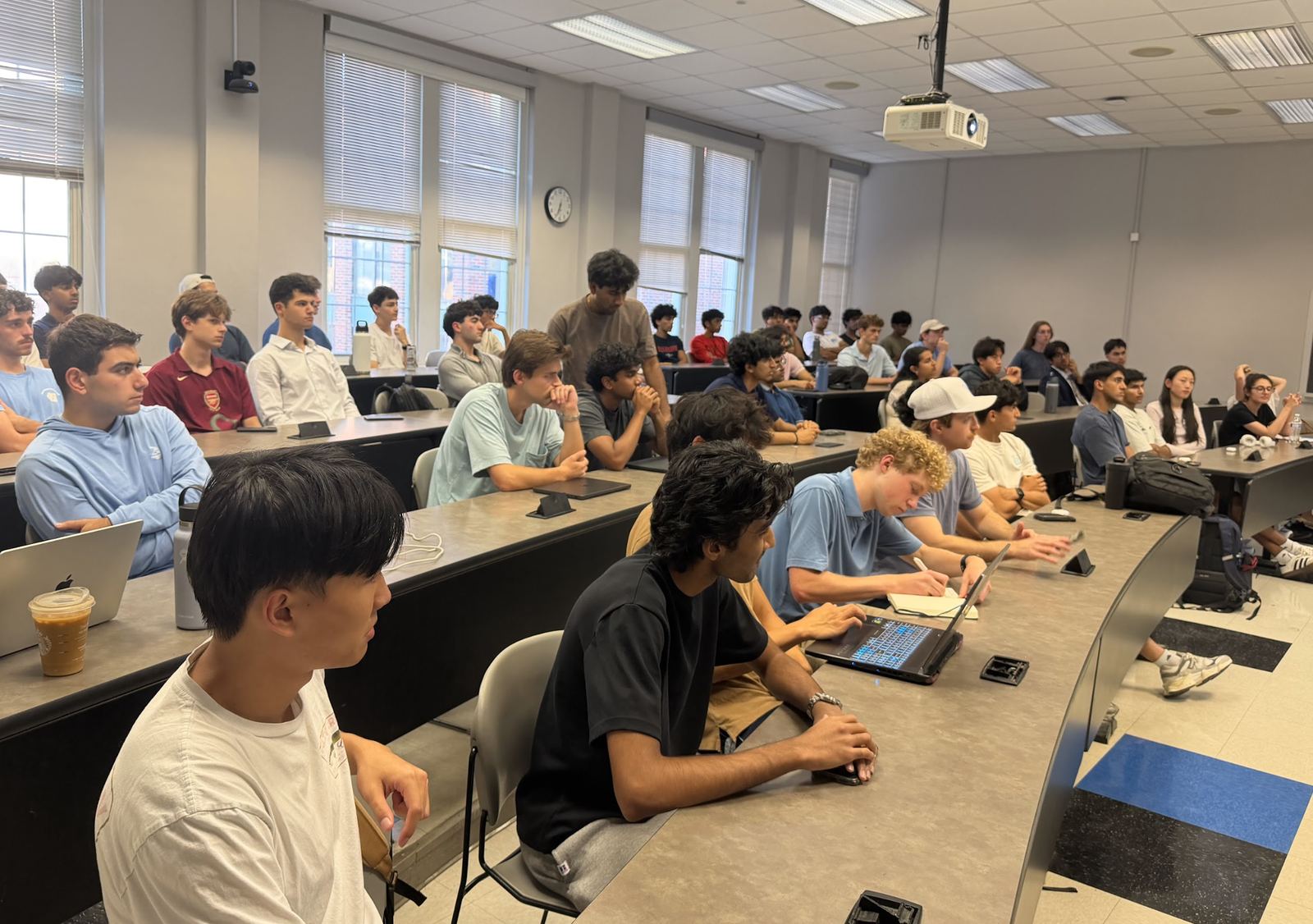 Students with laptops and notebooks following along in a lecture hall